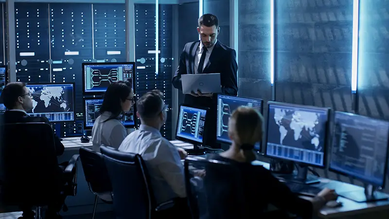 Professional IT Engineers Working in System Control Center Full of Monitors and Servers