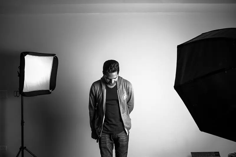 Grayscale photography of man standing in studio