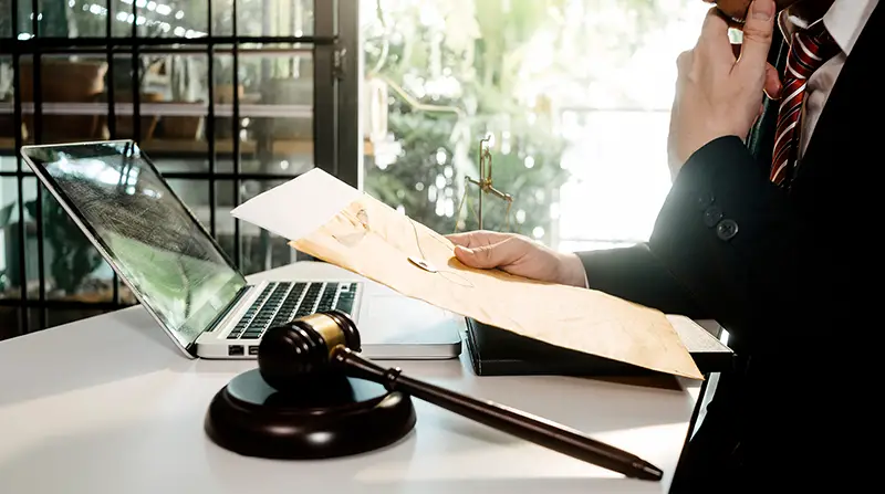 Lawyer discussing contract papers with brass scale on desk in office.