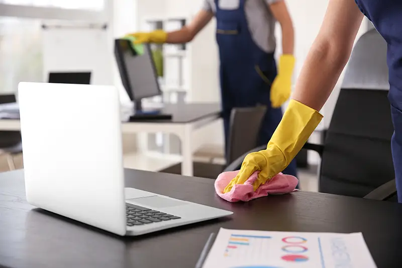 Janitor wiping table in office - commercial cleaning