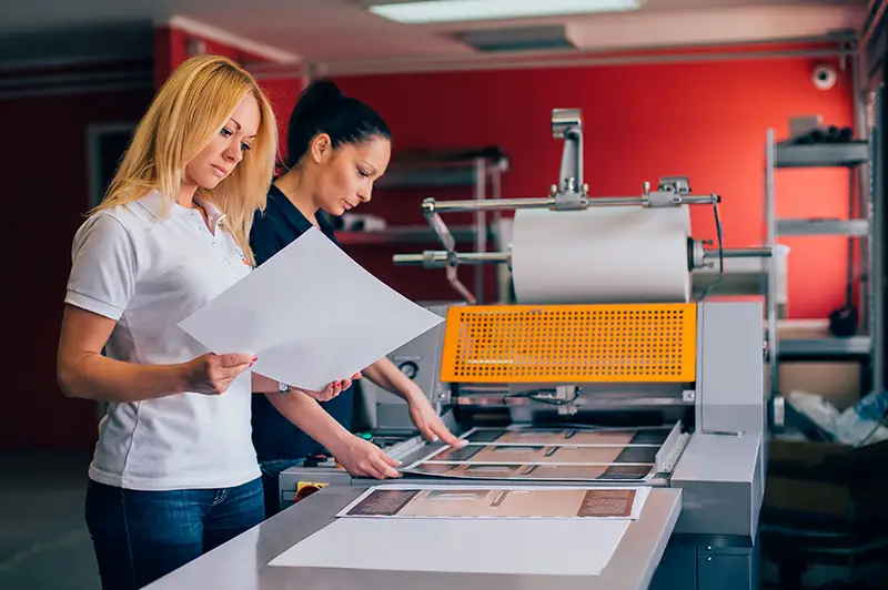 Two young woman working in printing factory.