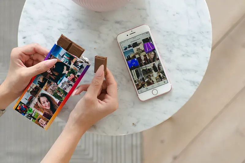 Person holding chocolate bars with iPhone silver on the table