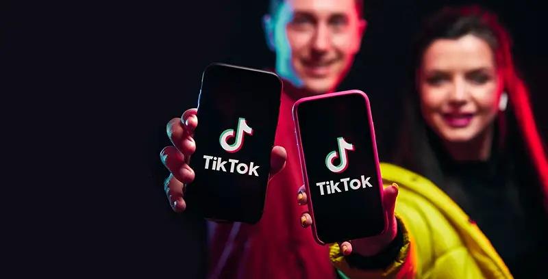 Young girl and boy (blogger) posing with smart phone and making video content in Tik Tok