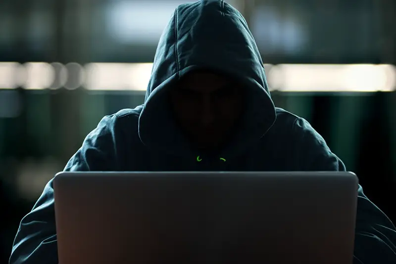 Person in black hoodie using laptop