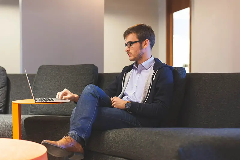 Man sitting in the couch working on his laptop