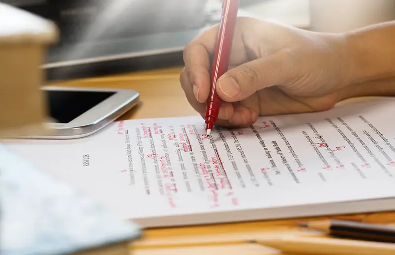 Person holding red pen while writing