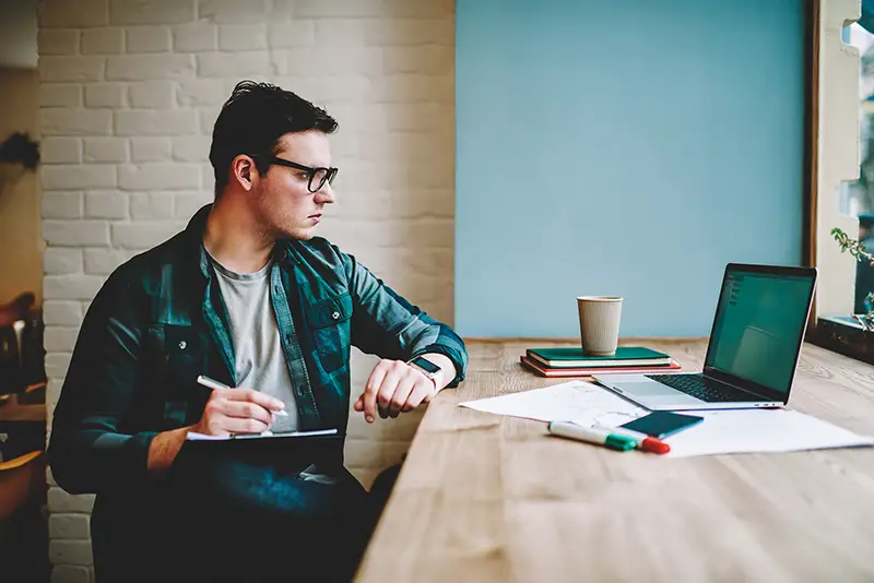 Pensive hipster guy in eyewear watching training webinar on laptop computer spending time on e learning,