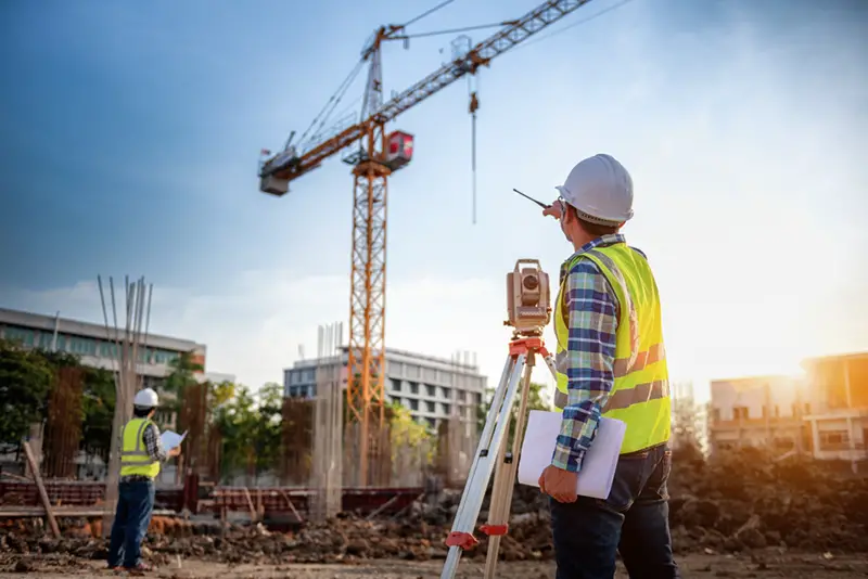 Surveyor equipment. Surveyor's telescope at construction site looking across site with a crane. Surveying for making contour plans is a graphical representation of the lay of the land startup construction work.