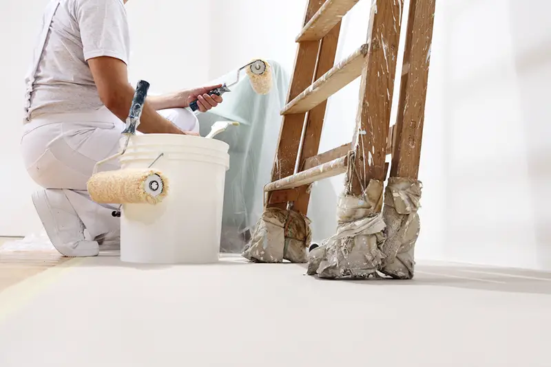 painter from painting company at work with a roller, bucket and ladder, bottom view