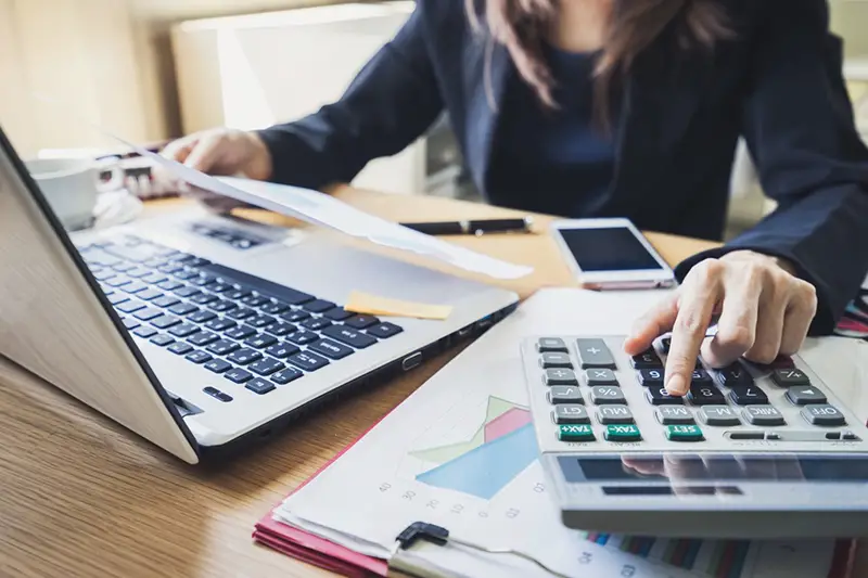 Woman using laptop and calculator for accounting