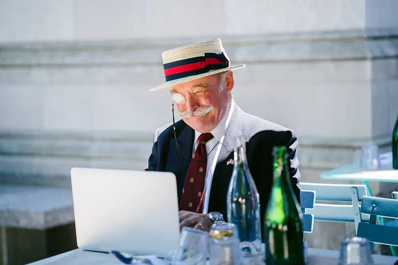 Old man wearing hat using laptop
