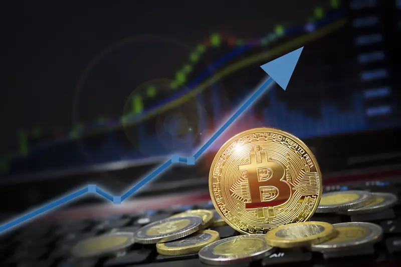 Bitcoin currency rising arrow price record highs on keyboard computer with golden bitcoin and other currencies.