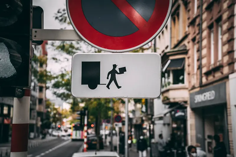 sign for delivery next to stop sign on post