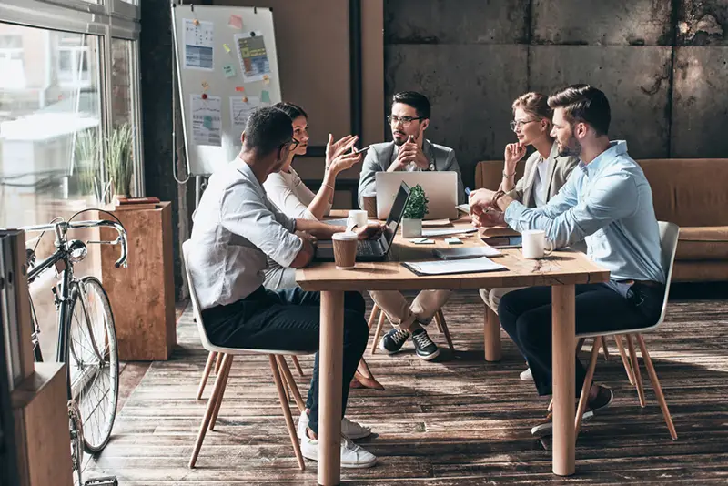 Confident and successful team. Group of young modern people in smart casual wear discussing business while sitting in the creative office