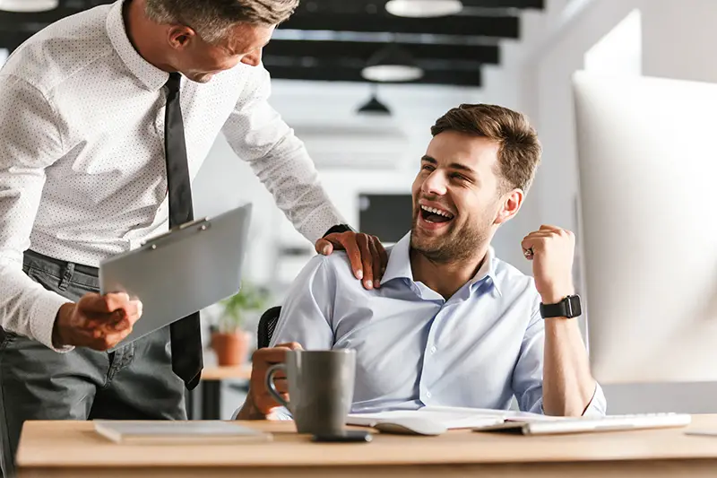 Happy emotional men colleagues in office working with computer.