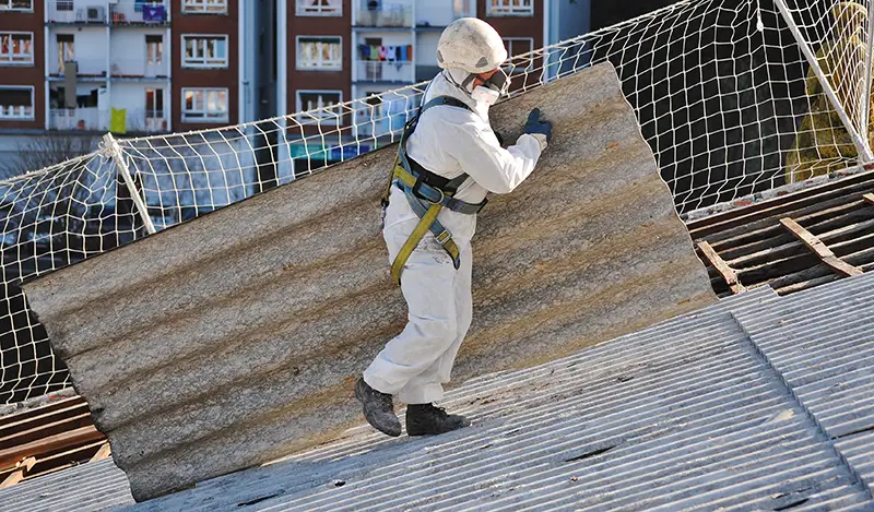 Man wearing safety protective gear carrying asbestos for roofing