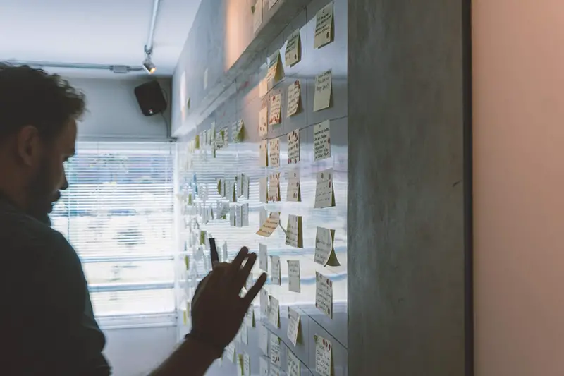 man putting sticky notes on a wall