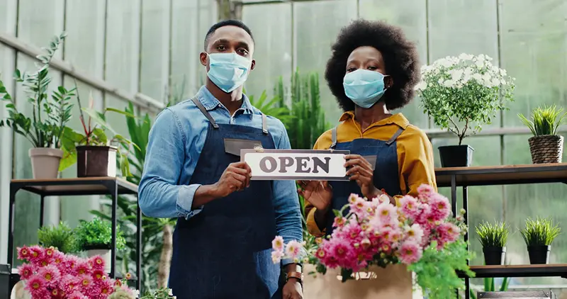 Man and woman holding an OPEN signage