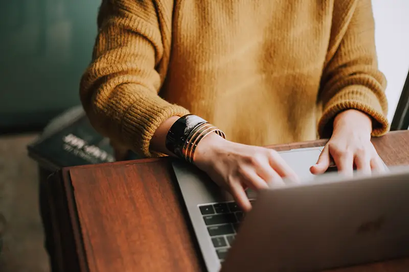 Person wering orange sweatshirt using laptop computer