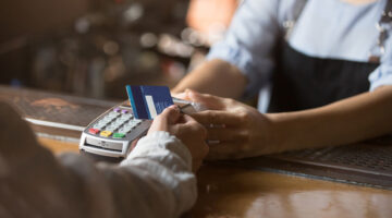 Contactless payment concept, female customer holding credit card near nfc technology on counter, client make transaction pay bill on terminal rfid cashier machine in restaurant store, close up view