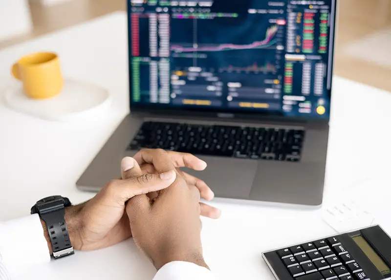 Man sitting on front of laptop with trading graph on the screen