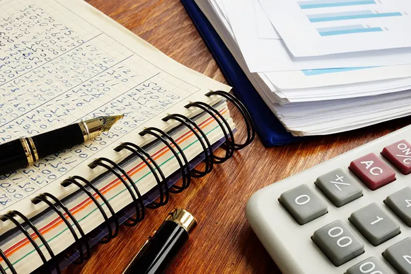 Log book and calculator on the top of wooden table