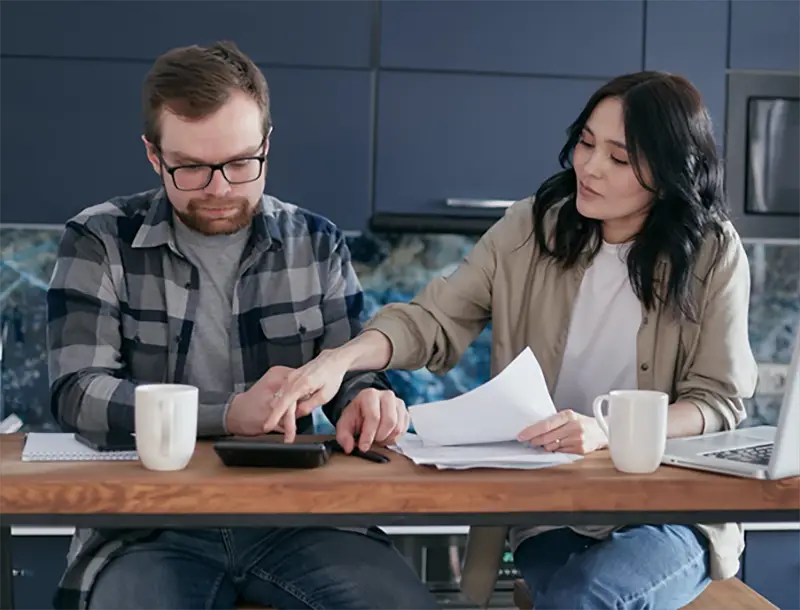 two people looking at bills and using calculator