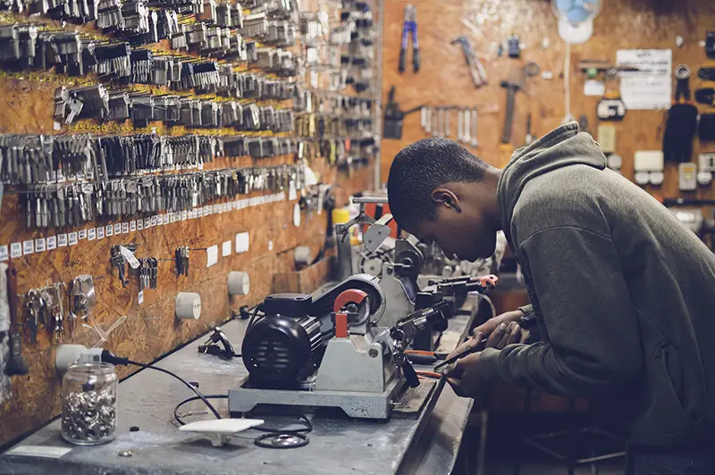 Young man working at work bench in key cutting shop