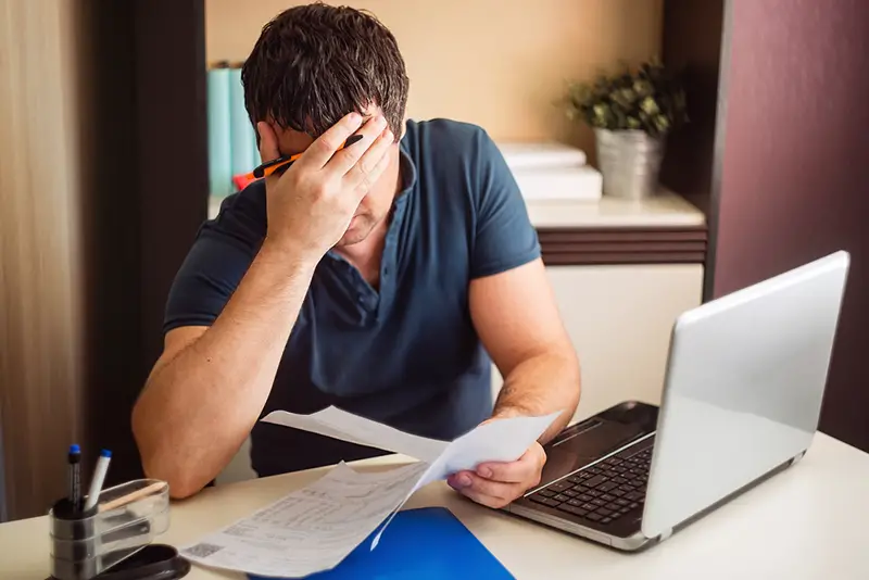 The shocked and disappointed man saw the bad news in the invoices. Frustrated man with documents.