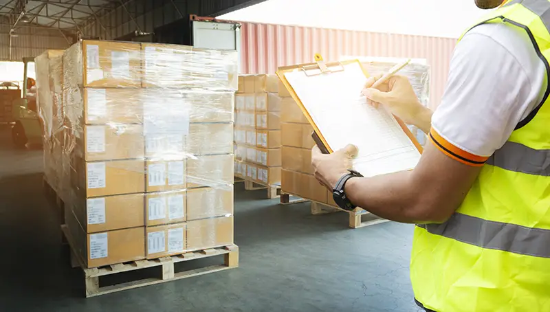 Man holding clipboard while checking items in a warehouse