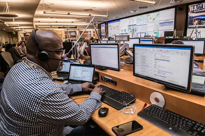 Bald guy taking calls in front of computers