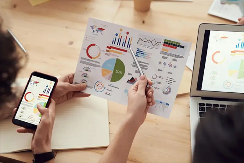 employees looking at business charts on a sheet of paper