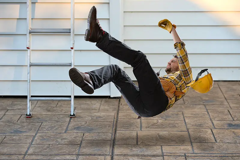 Worker with hard hat falling from ladder onto concrete floor