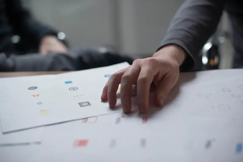 Person with his hand on printed white paper featuring logo images