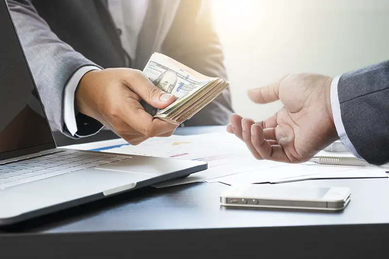 Two businessmen give and take US dollar banknote