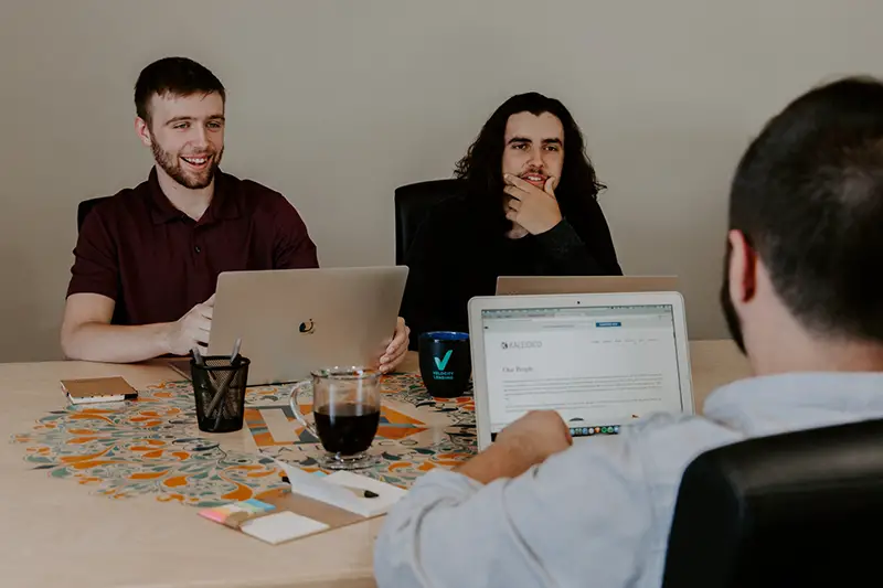 Three person sitting in front of table with laptop