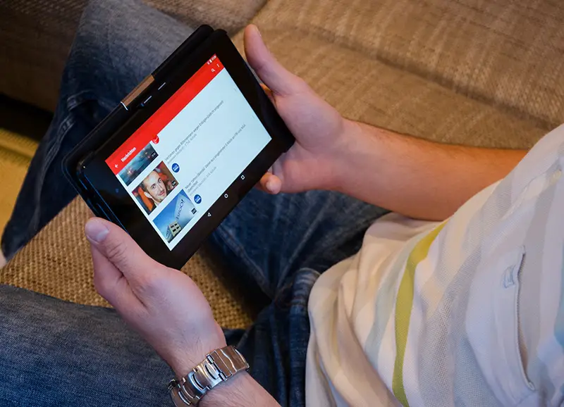 Person holding table computer watching YouTube channel