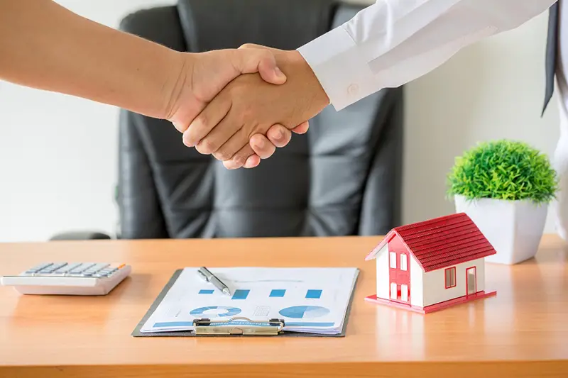 Side view hands of agent and client shaking hands after signed contract