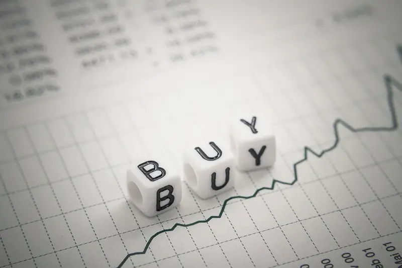 White dice with letter BUY on top of paper with graph