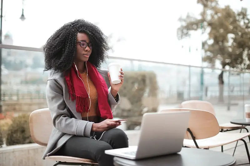 Woman sitting in front of her laptop while holding white cup