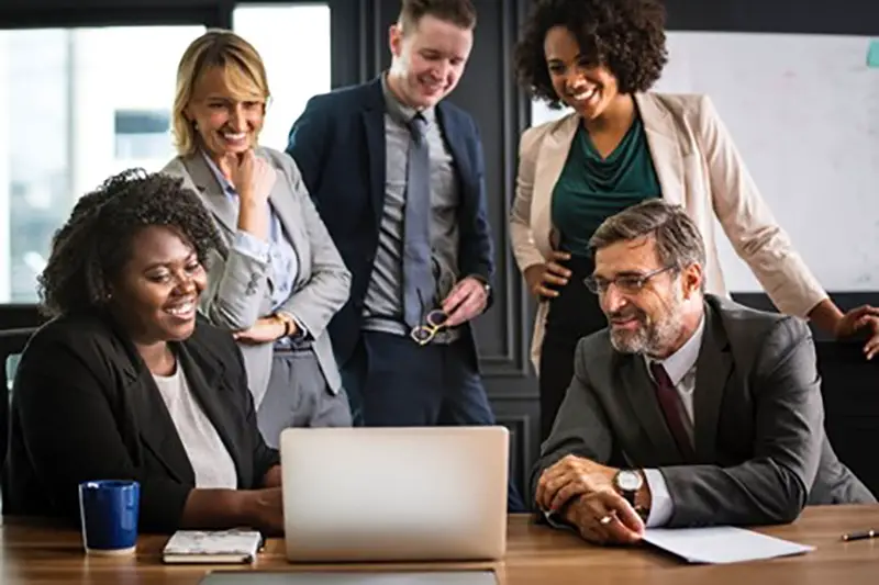 Business colleagues in front of silver laptop in their office