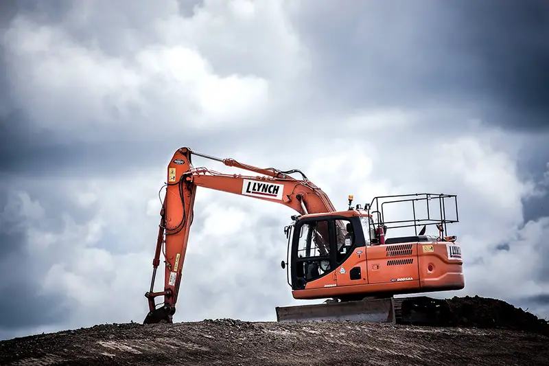 Orange excavator in the middle of wide land area