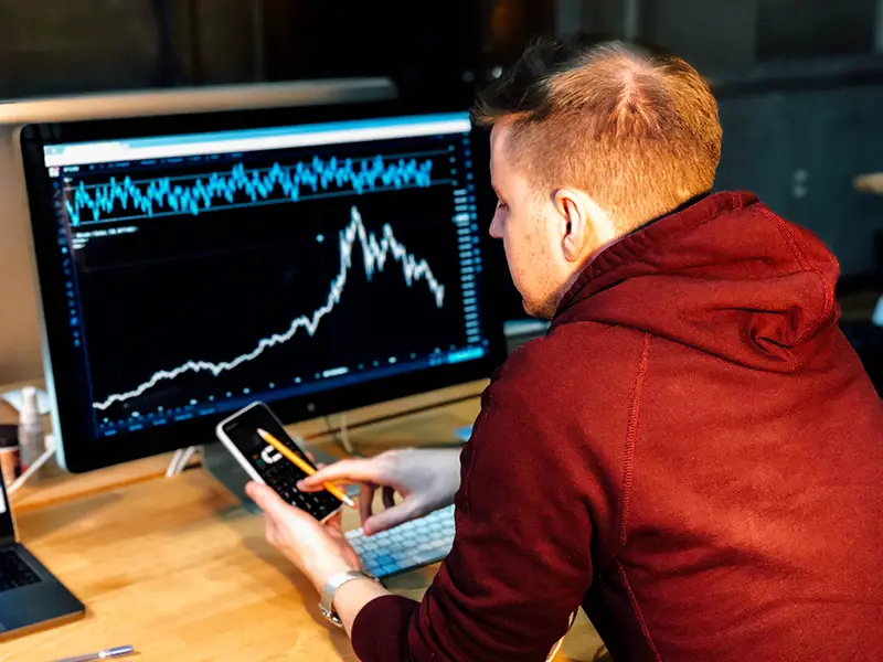 Man holding black smartphone in front of his computer