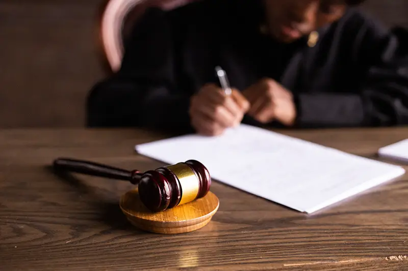 Person writing on white paper near gavel