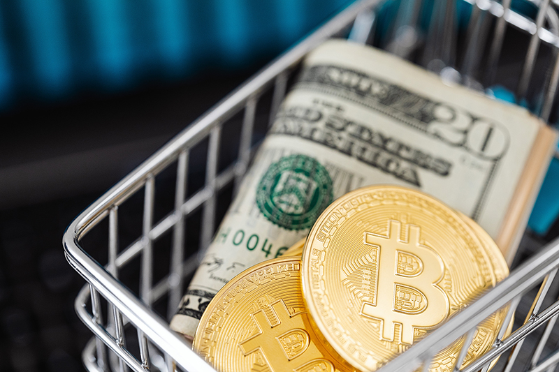 Bitcoin cryptocurrency in mini shopping trolley with dollar bills