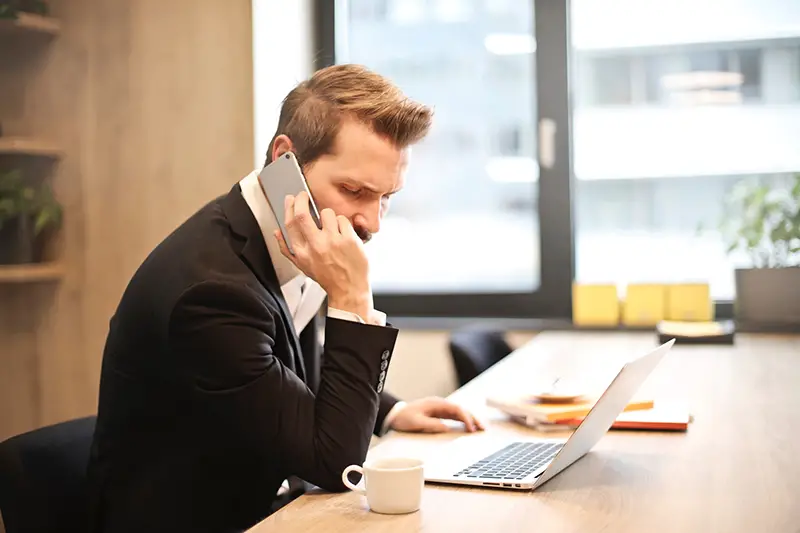 Man having a phone call in front of his laptop