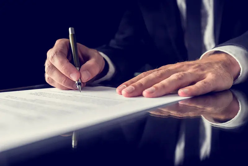 lawyer signing important legal document on black desk.