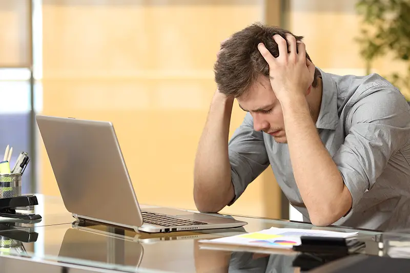 Worried businessman lamenting in front of a computer after a big mistake at office