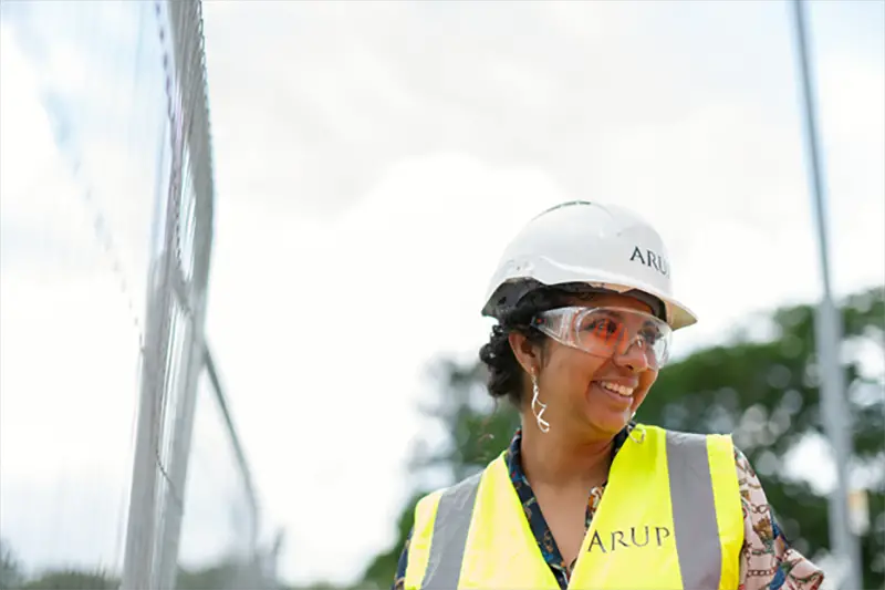 Female worker wearing hard hat and high visibility vest on work site