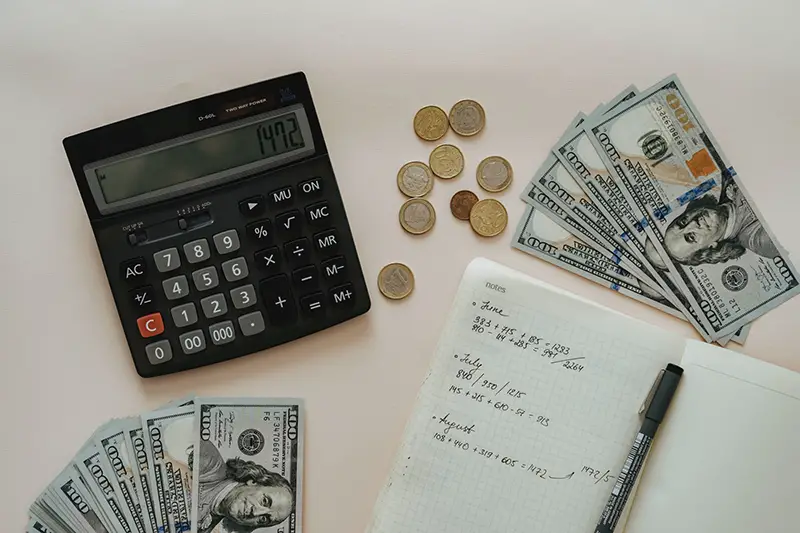 Black calculator beside coins and notebook